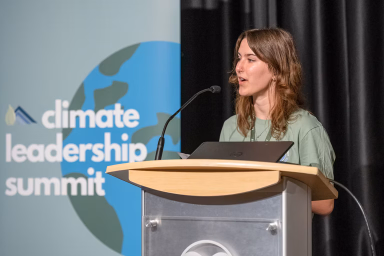 A female youth speaking behind a podium at the Youth Climate Leadership Summit