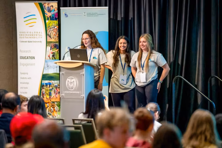 Three female students on stage at the Youth Leadership Summit