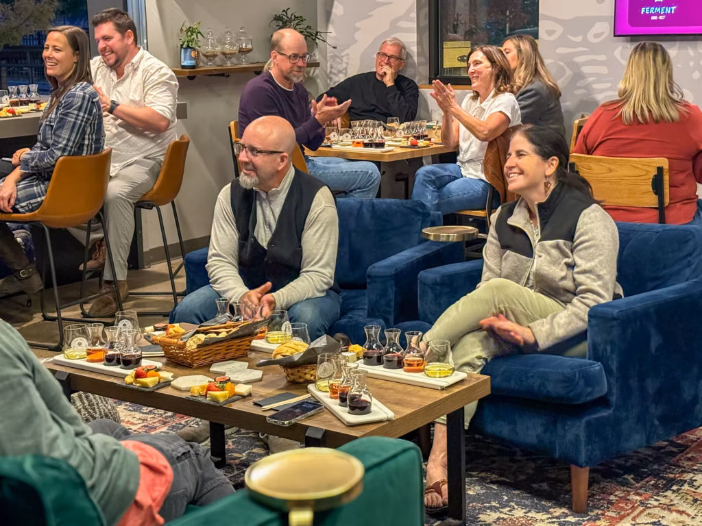 People at the Sustainable Living Association Wine and Cheese Pairing event sitting with flasks of wine and trays of cheese in front of them